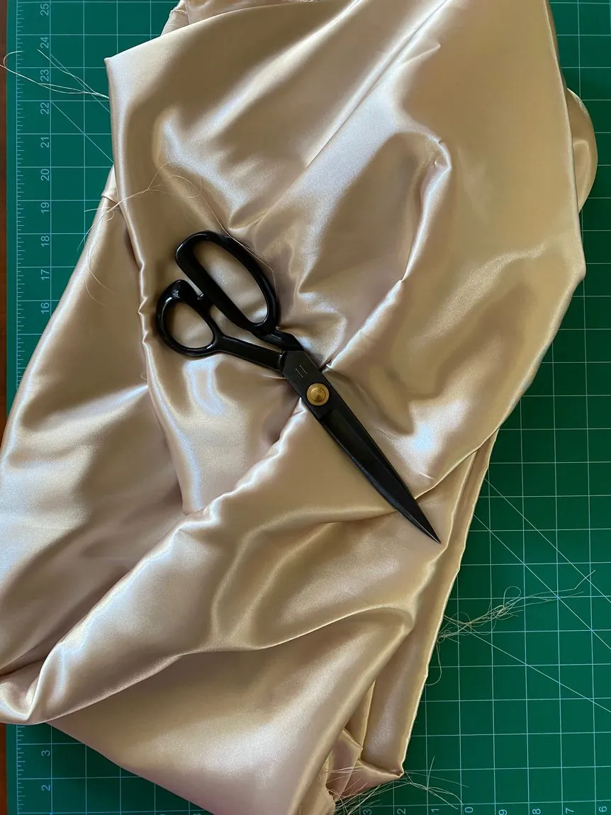 Champagne satin laid out for cutting with tailoring shears