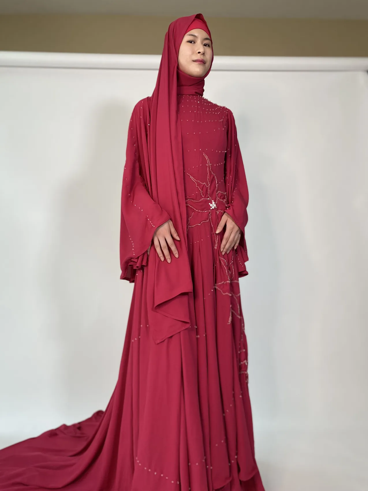 Model in a crimson beaded couture gown with a train by HK Collection